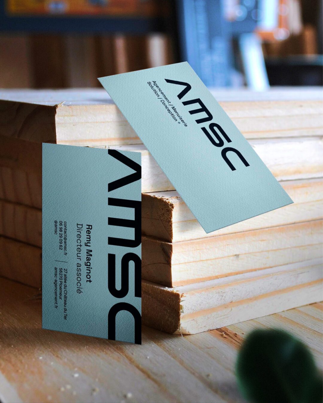 Cartes de visite AMSC posées sur des planches de bois — design et identité visuelle réalisés par Pois Chiche Design à Lorient.