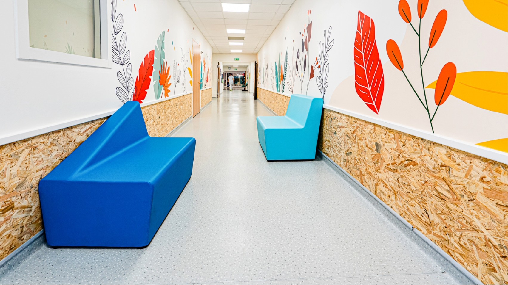 Couloir du Centre Kerpape décoré par Pois Chiche Design, avec fresques florales colorées et assises bleues.