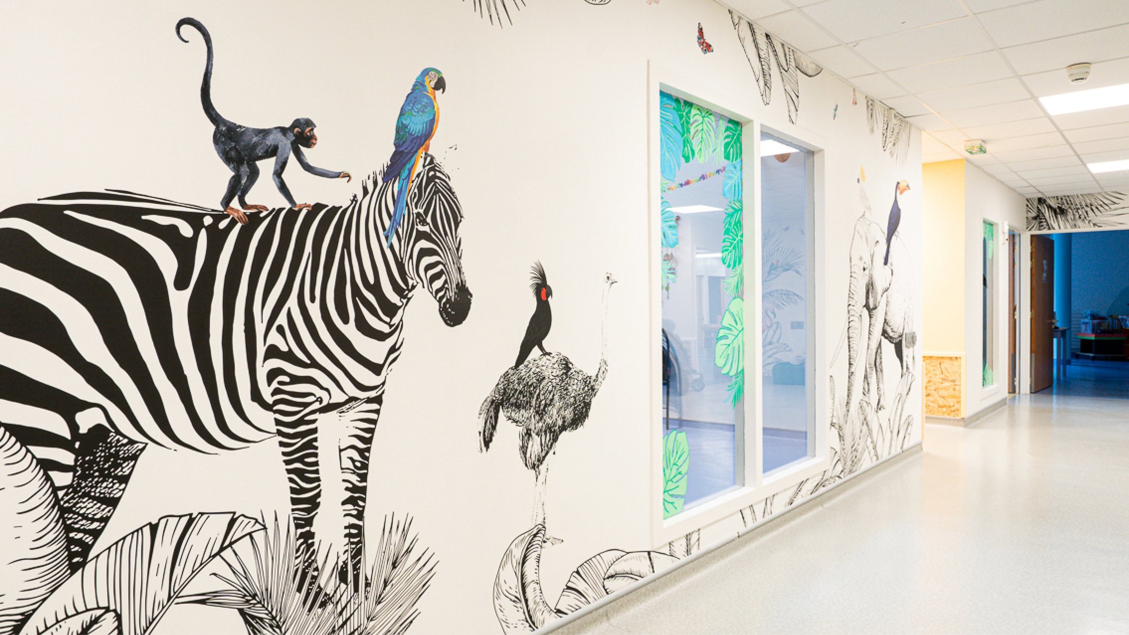 Fresque murale du Centre Kerpape : zèbre, singe, perroquets et végétation illustrés par Pois Chiche Design dans un couloir de rééducation.