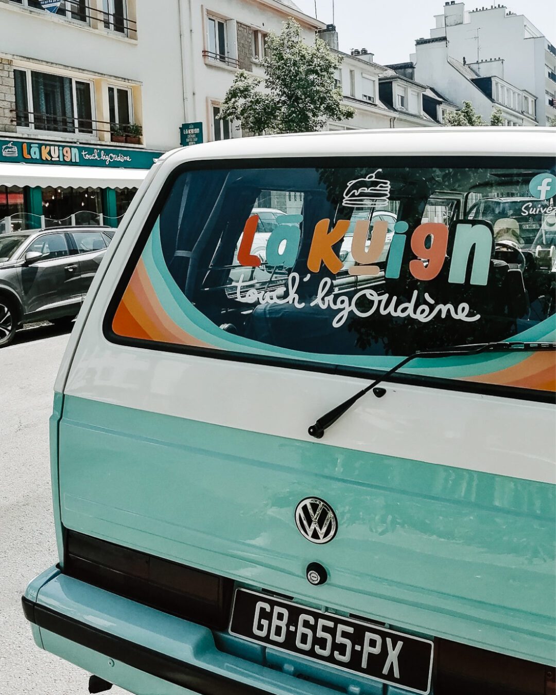 Van Volkswagen vintage avec le logo coloré Lã Kuign Touch’ Bigoudène sur la vitre arrière, branding réalisé par Pois Chiche Design à Lorient.