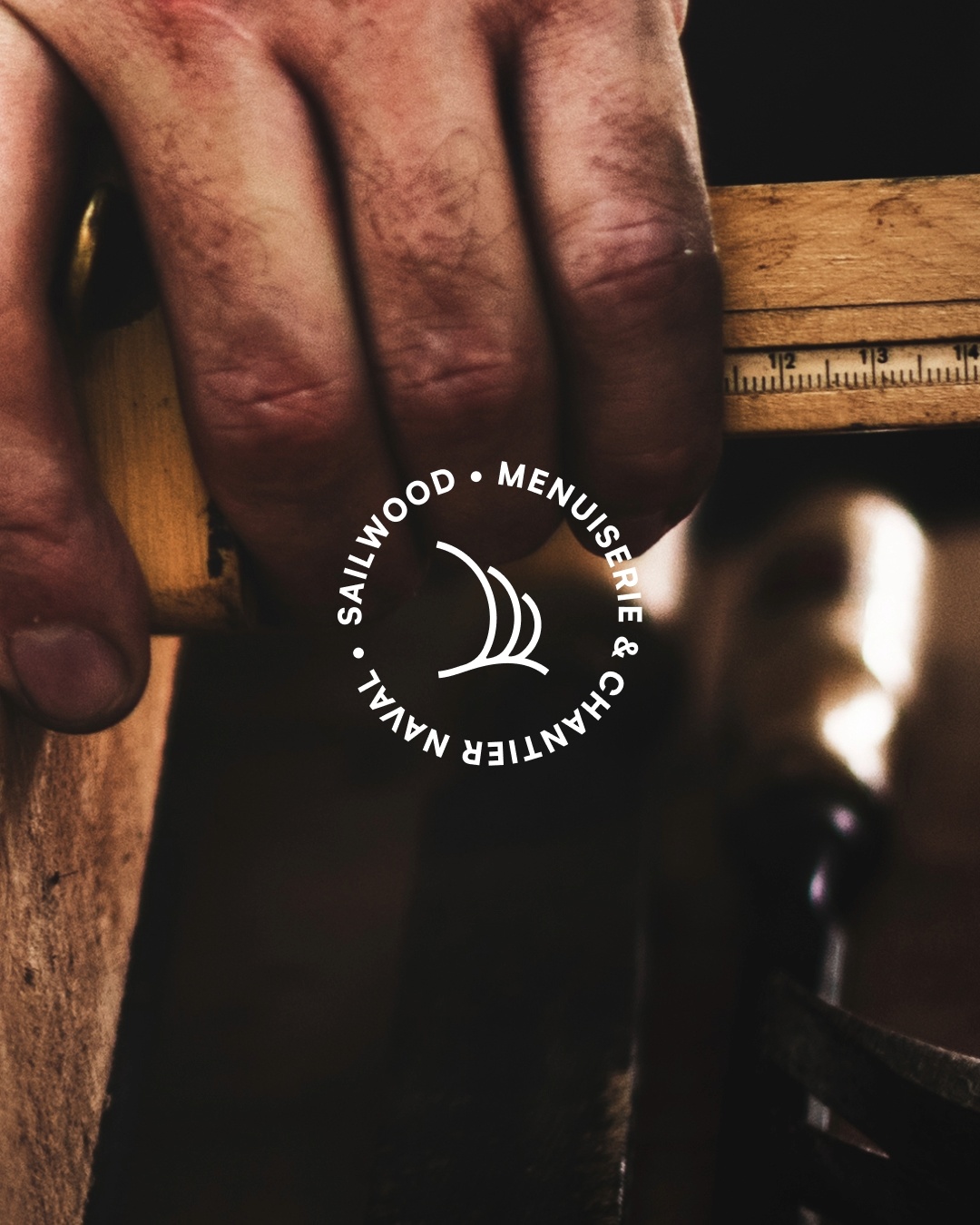 Main d’artisan travaillant le bois dans un atelier de menuiserie navale Sailwood